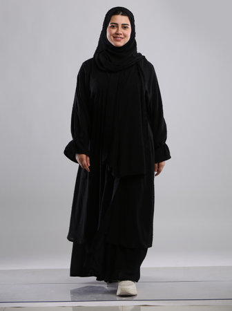 Portrait of a beautiful muslim woman wearing hijab standing on gray backgroundの写真素材