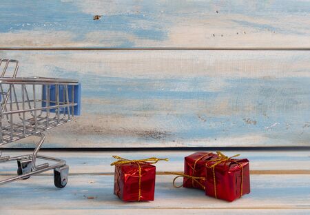 Shopping cart and Red gift box with sale concept on wood background.の写真素材