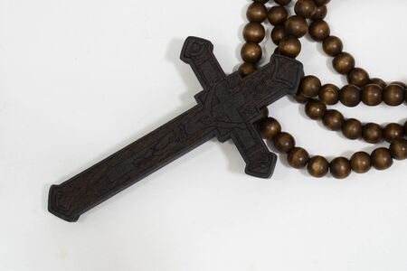 rosary beads with cross made of black wood on a white background, selected focus on christ, narrow...