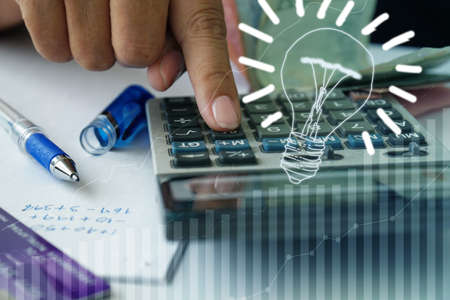 Calculator and graph next to a light bulb, the concept of energy. Finance.の写真素材