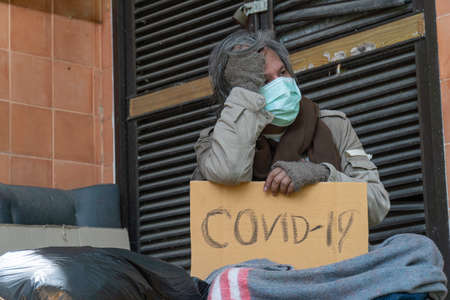 A homeless man carries a cvid-19 sign, a problem of modern megacities.の写真素材
