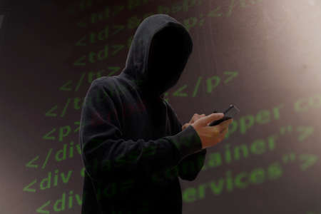 Computer hacker in mask and hoodie over abstract Data thief background.