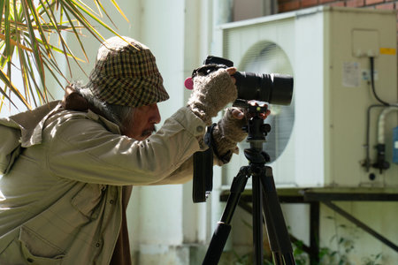 Senior man using a camera to take a photo of his home.の写真素材