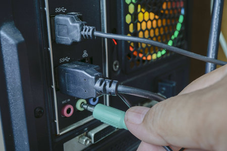 Close-up of technician hand connecting cable to power supply cabinet.