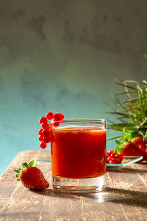 Healthy smoothie with red fruits, delicious strawberries and red currants on wooden table