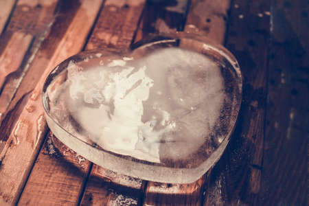 frozen ice heart icy heart Cold heart on brown woods blur backgroundの写真素材