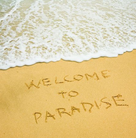 welcome to paradise written in the sandy beachの写真素材