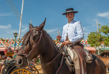 SEVILLE, SPAIN - April, 25: Horse rider with a glass of manzanilla at the Seville's April Fair on April, 25, 2012 in Seville, Spainのeditorial素材