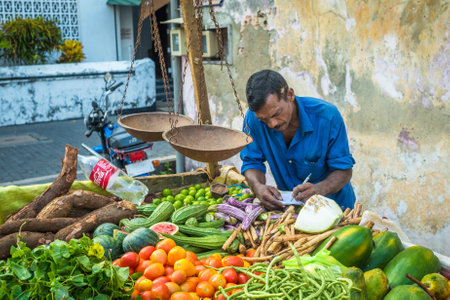 GALLE, SRI LANKA - February, 14, 2016: Street vendor with vegetables and vintage scalesのeditorial素材