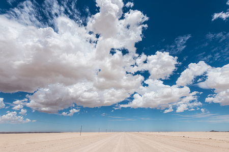 vibrant image of desert road and blue cloudy skyの写真素材