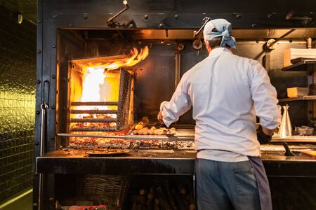 Chef cooking meat and sausages on grill. Focus on grill.の写真素材