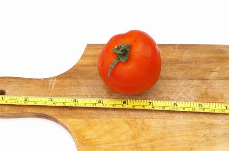 Measure a tomato on a wooden plateの写真素材