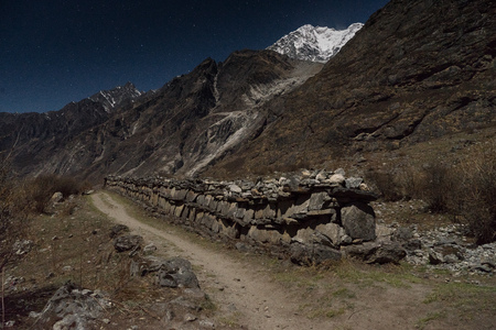 Old wall ruins and snow peaks at nightの写真素材