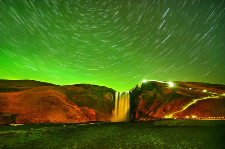 View of the northern light with star trails at Skogafoss in Iceland.の写真素材