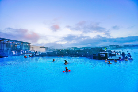 View of the Blue Lagoon pool and visitor's building at dusk with lots of tourists bathing in Blue Lagoon, Iceland on January 27, 2017.のeditorial素材