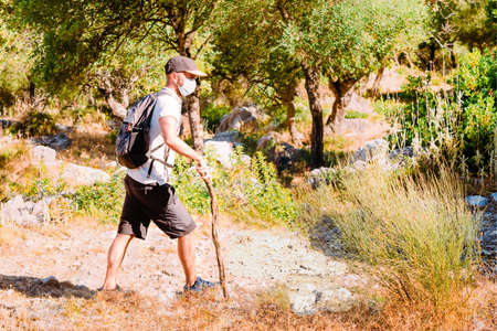 Young man with a medical mask hiking on a road of the ancient Roman Empire. Selective focusの写真素材