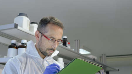 Scientist writing data from his research in the laboratory. Selective focus.の写真素材