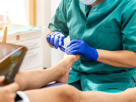 Female podiatrist doing chiropody in her podiatry clinic. Selective focus