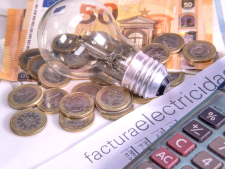 Electricity bill posted in Spanish, next to a calculator, a bulb and money. Electricity price concept.の写真素材