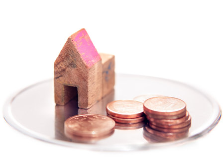 Toy small house and coins on white background. Select focus.