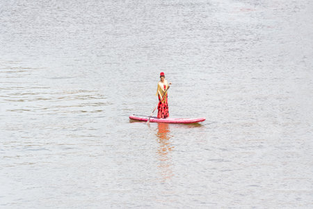 Seville, Spain - May 04, 2022 : Woman in flamenco dress on a paddle surf board on the Guadalquivir...