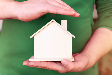A woman holding and covering house model with handの写真素材