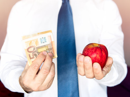 Man hands with money and an apple. Price and investment concept in food. Select focus.の写真素材