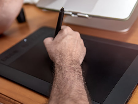 Man drawing with digital pen on graphic tablet