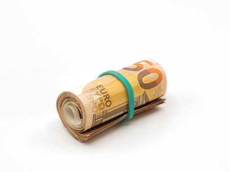 A roll of 50 Euro banknotes, bound together with a green rubber band, isolated on a white background.の写真素材