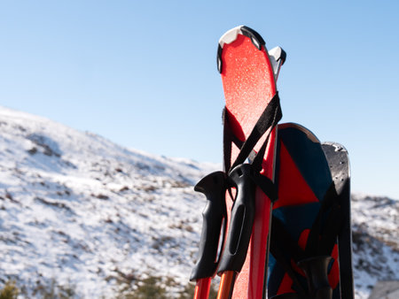 Skis and poles against a snowy mountain backdrop, ready for an adventurous day.の写真素材