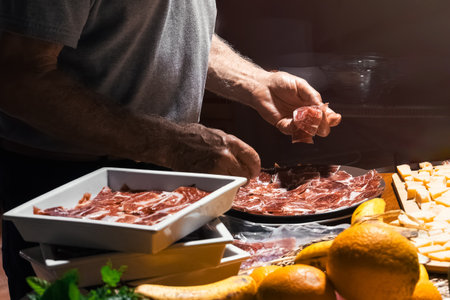 Chef places cured meats and cheese on a charcuterie board.の写真素材