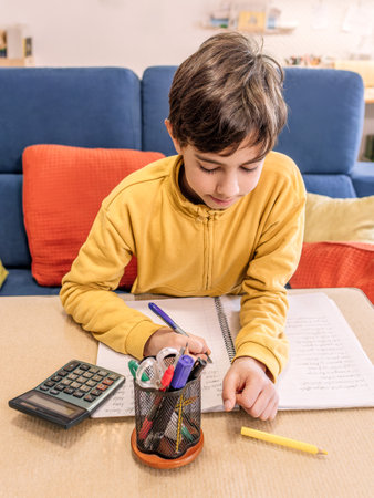 Student with calculator and pens focused on homework at living room table.の写真素材