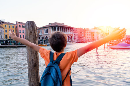 Joyful Boy with Backpack Overlooking Venice Canalの写真素材