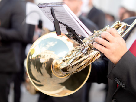 Close up of musician hand playing a golden french horn during outdoor street parade