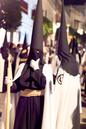 View of penitents in traditional hoods and robes during a night processionのeditorial素材