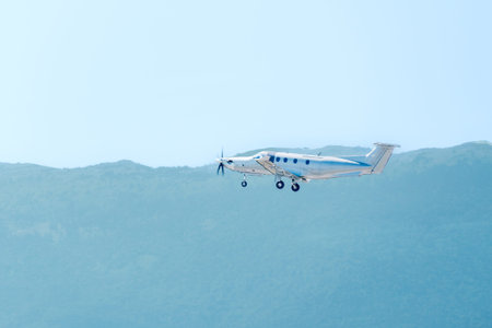 Single engine turboprop private airplane flying over green mountain landscapeの写真素材