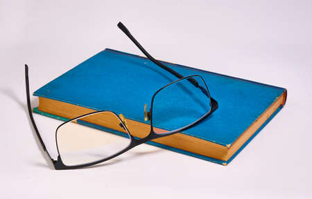 Glasses was taken off and put on a blue book. White backgroundの写真素材