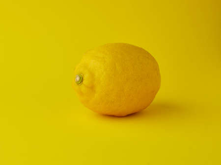 Whole lemon on yellow backgroundの写真素材