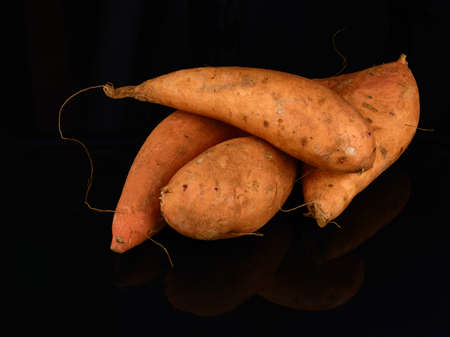 fresh four sweet potatoes on dark backgroundの写真素材