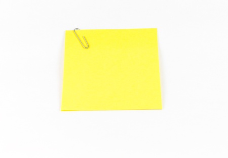 Yellow sticky note and clip on white.