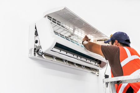 Young repairman fixing a ductless minisplit air conditioning systemの写真素材