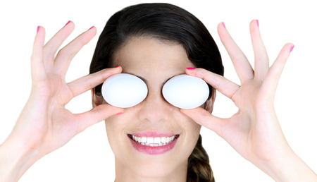 Young Woman holding a couple eggs over her eyes