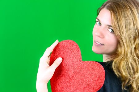 Young Woman holding a Heart on green backgroundの写真素材