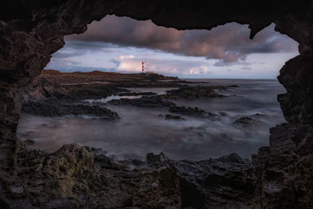 view of a lighthouse and the sea from inside a cave