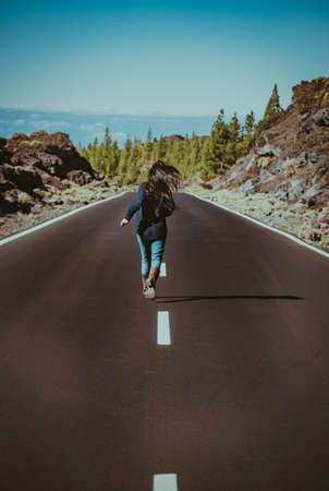 long haired young woman runs down the road feeling free and relaxedの写真素材