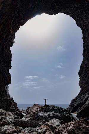 stone arch by the sea where you see a man with open armsの写真素材