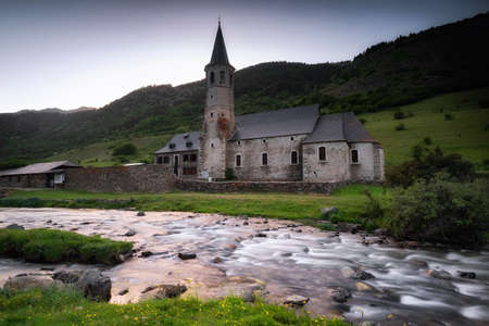 river with lots of green vegetation and an old church constructionの写真素材
