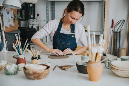 young artisan woman working with her hand a piece of ceramic focus on person