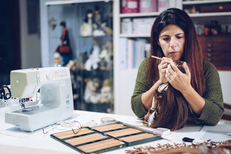A young woman paints the face of her rag dollの写真素材