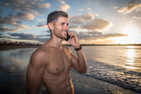 a young man talking on the phone on the beach. relaxation modeの写真素材